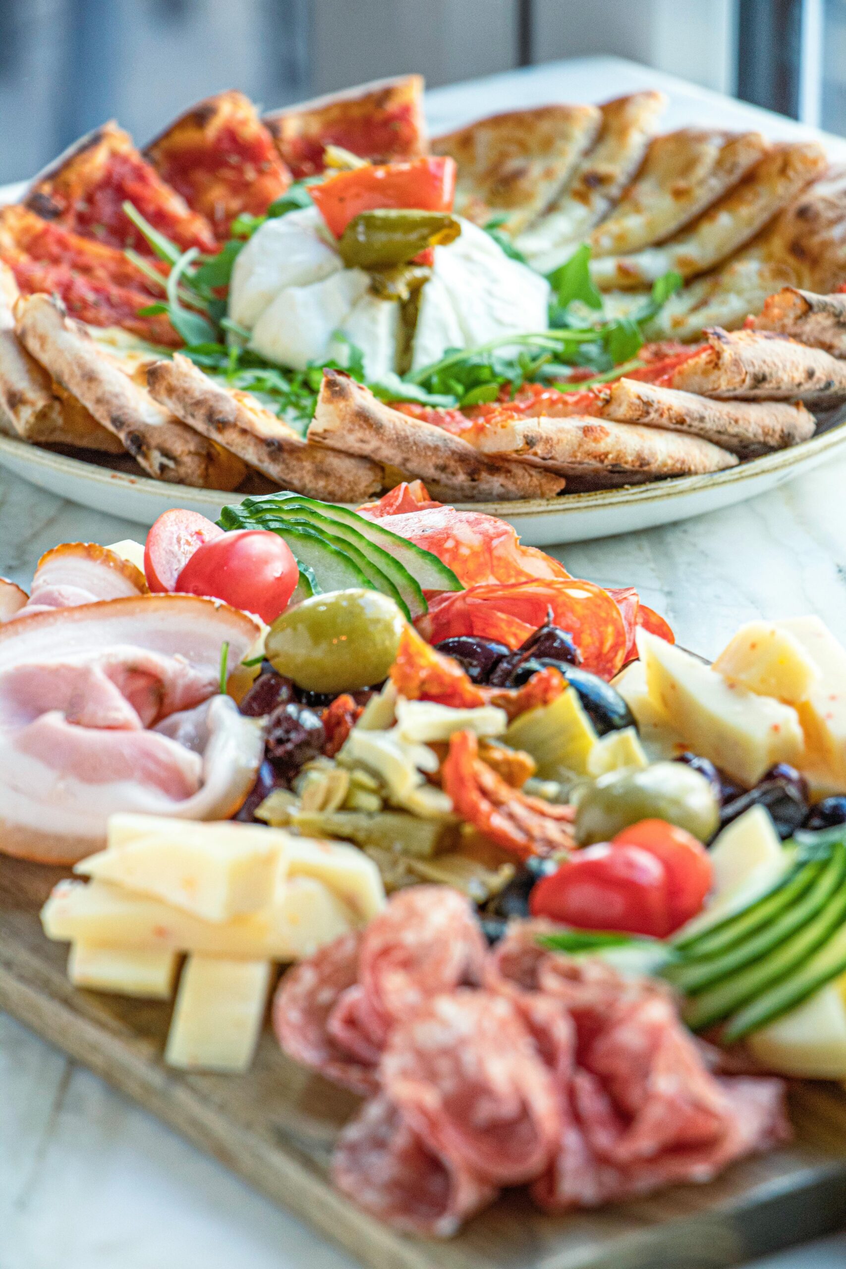 Enticing antipasto platter with cured meats, cheese, vegetables, and pizza slices.