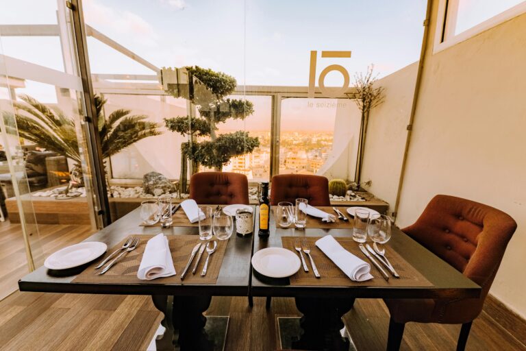 Luxurious dining setup in a rooftop restaurant overlooking the cityscape at sunset.