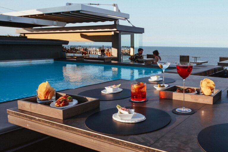 Elegant rooftop dining by the pool with sea views, featuring gourmet snacks and cocktails.