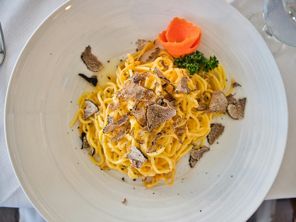 Delicious gourmet pasta served with truffle shavings and a vibrant garnish on a white plate.