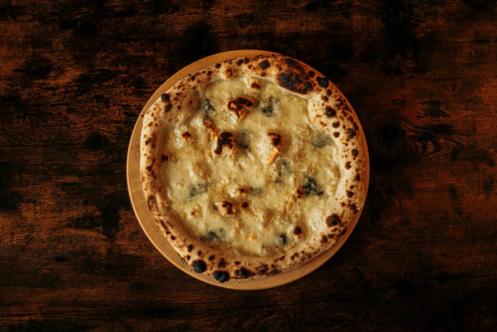 Delicious four cheese pizza displayed on a rustic wooden table, perfect for food lovers and culinary enthusiasts.