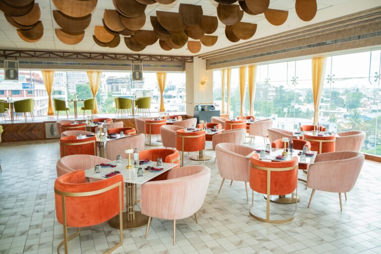 Stylish rooftop restaurant featuring vibrant seating and modern decor with panoramic city views.